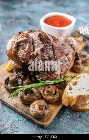 Close-up ram alla griglia della gamba con funghi, verdure, spezie su un tagliere. La carne halal e cibo Foto Stock