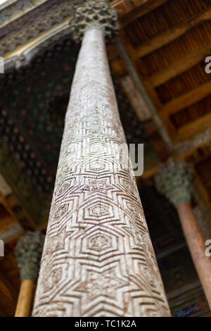 Olmo tradizionale scultura in legno colonne ornate con kokands e soffitto. Le colonne di legno sostenere il tetto del iwan. Uzbekistan tradi nazionale Foto Stock