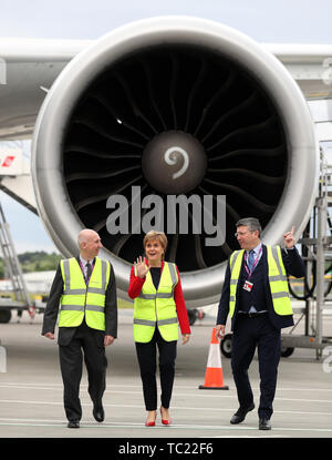 Primo Ministro Nicola Sturgeon con Sir John Elvisge (a sinistra), Presidente dell'aeroporto di Edimburgo insieme all'Amministratore Delegato Gordon Dewar sulla asfalto dell'aeroporto di Edimburgo, mentre apre ufficialmente un'espansione del terminal. £80 milioni sono stati investiti nell'espansione del terminal che ha fornito nuove sale arrivi internazionali e nazionali e aree di ritiro bagagli, nuovi cancelli e aree salotto, nuovi stand aerei, nuove sale e nuovi punti vendita al dettaglio e di cibo e bevande. Foto Stock