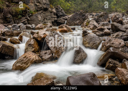 Una cascata di torrente di montagna si piega e si insinua intorno rocce e massi, lunga esposizione per creare la sfocatura in movimento per l'acqua, nessuno nell'immagine Foto Stock