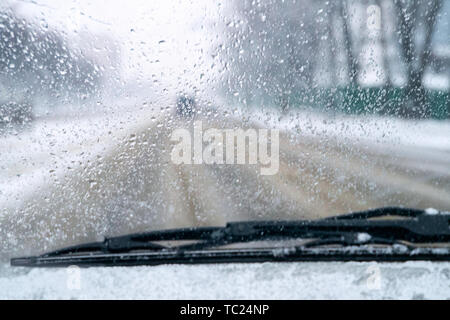 La scarsa visibilità sulla strada. auto corse su strada sdrucciolevole. la neve e la pioggia sul parabrezza. sfondo sfocato. cattive condizioni meteorologiche Foto Stock