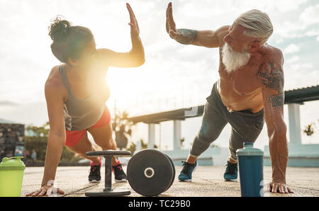 Coppia Fitness push facendo esercizio di ups al tramonto outdoor - Happy atleti rendendo palestra di allenamento al di fuori della sessione Foto Stock