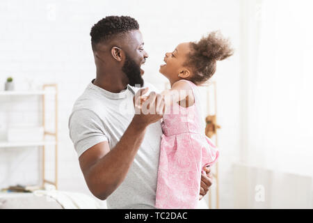 Allegro uomo nero ballando con la sua piccola figlia Foto Stock