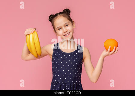 Carino allegro ragazza con le banane fresche e frutta di arancia Foto Stock