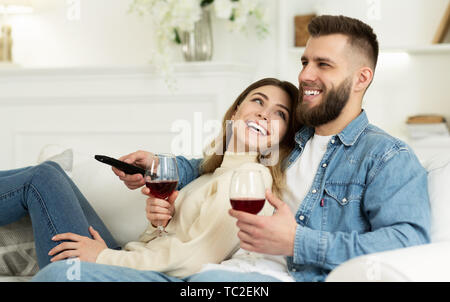 Coppia felice di bere vino e guardare la TV a casa Foto Stock