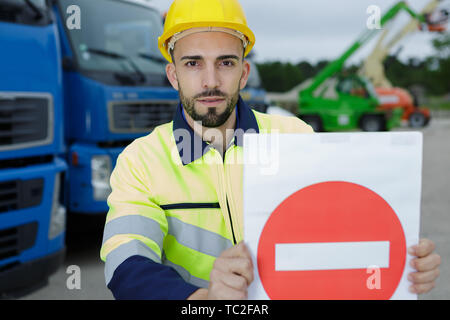 Operaio edile tenendo un cartello Foto Stock