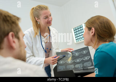 Medico uomo e donna che parlano ed esaminare la colonna vertebrale dei risultati di MRI Foto Stock