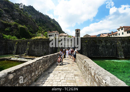 Tourist attraversando il ponte in prossimità di Vrata od Škurde nella città vecchia di Kotor. Foto Stock