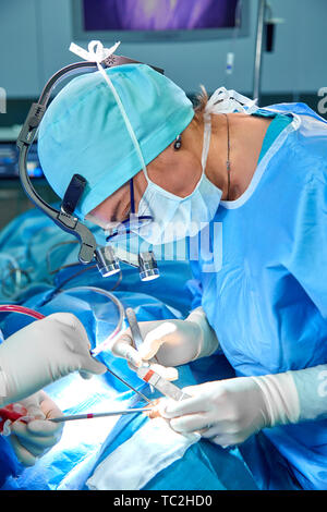 Close-up di un funzionamento del team di chirurgia. Un team di professionisti medici chirurghi con gli assistenti di sala operatoria. Blu luce medica. La chirurgia, salvataggio Foto Stock