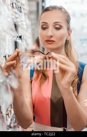 Donna shopping occhiali scegliendo tra i modelli Foto Stock