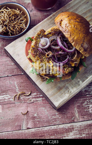 Specialty Bug o insetto hamburger con patatine fritte mealworms croccante su un panino croccante con cipolla pomodoro e rucola visto dal di sopra Foto Stock