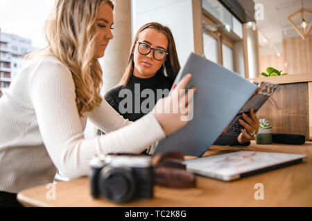 Due gravi Giovani blogger discutendo sulla pubblicazione in Cafe Foto Stock