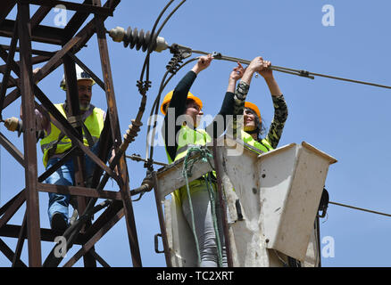 (190605) -- HOMS, 5 giugno 2019 (Xinhua) -- Due donne lavoratori elettrici fissare un alta tensione linea elettrica nella provincia di Homs, centrale in Siria il 30 maggio 2019. Come la guerra in Siria rumbled on, donne siriano ha iniziato a impegnarsi in più posti di lavoro rispetto ad una normale lavoro di ufficio e di educazione dei figli, come un gran numero di uomini avevano aderito all'esercito o ha lasciato il paese per cercare rifugio. I posti di lavoro che le donne del paese sono sempre più facendo includono la riparazione di automobili, alla guida di autobus o taxi, e ancor più interessante, utilizzando una gru per raggiungere le linee elettriche ad alta tensione e fissarli, malgrado tutte le sfide come la famiglia Foto Stock