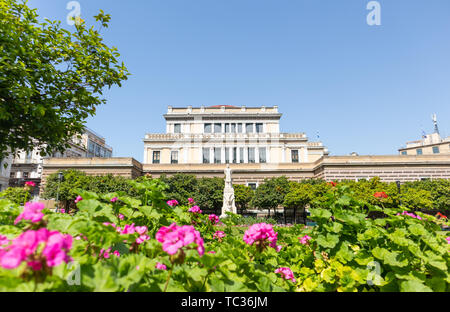 Aprile 28, 2019. Atene, Grecia. Statua di Charilaos Trikoupis nella parte anteriore del Vecchio Parlamento. Alberi e fiori circondano la scultura bianco. Blue sky bac Foto Stock