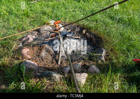 Saporite salsicce gocciolamento con lardo cotto su un fuoco aperto. Un camino in un giardino di casa. Stagione della primavera. Foto Stock