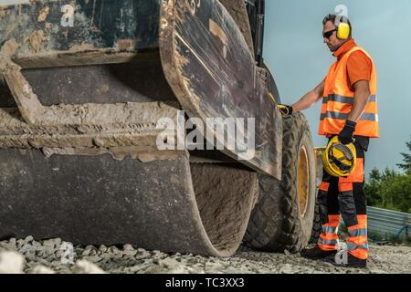 Funzionamento del rullo su strada. Caucasian lavoratore edile e per impieghi pesanti macchinari per la costruzione di strade. Foto Stock