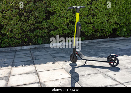 Lonely scooter elettrico parcheggiato in attesa di qualcuno a noleggio Foto Stock