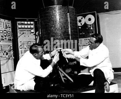 Gli ingegneri della NASA Stanley R Peterson e Ray Bowerman controllo dell'Early Bird, il mondo il primo satellite di comunicazione, presso Hughes Aircraft Company in Glendale, California, 1965. Immagine cortesia Nazionale Aeronautica e Spaziale Administration (NASA). () Foto Stock