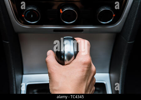 Vista ritagliata dell'uomo tiene la maniglia del cambio marcia in auto Foto Stock