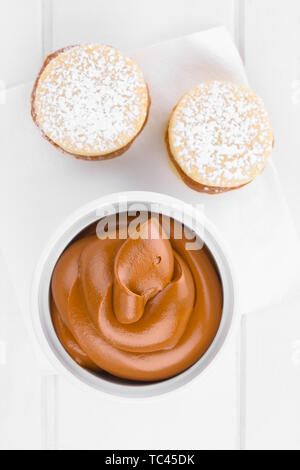 Latin American Dolce caramello-come Manjar o Dulce de leche utilizzato come diffondere o riempimento nella cottura in forno con alfajor cookie sul lato, fotografato tettuccio Foto Stock