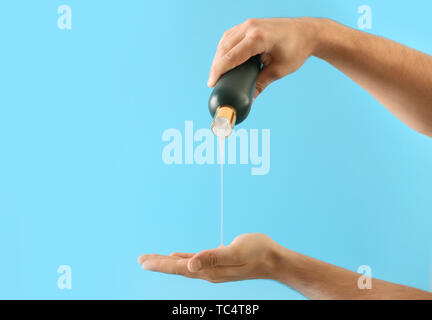 Mani maschio con bottiglia di shampoo sul colore di sfondo Foto Stock