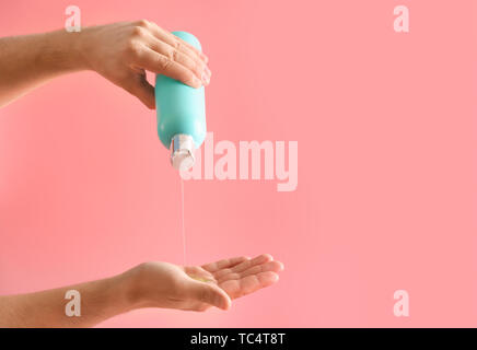 Mani maschio con bottiglia di shampoo sul colore di sfondo Foto Stock