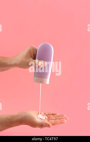 Mani maschio con bottiglia di shampoo sul colore di sfondo Foto Stock