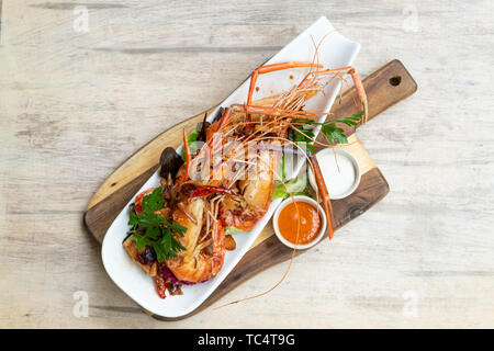 Close up di grigliate di carne saltata grande gamberi di fiume piatto di frutti di mare insalata mix salsa piccante la maionese in un pannello di legno piastra fantasia naturale isolato luce posteriore Foto Stock