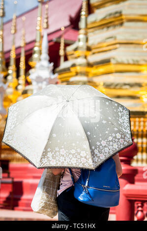 Una donna tailandese tiene un ombrello per proteggersi dal sole al Tempio Wat Phra Sing, Chiang mai, Thailandia. Foto Stock