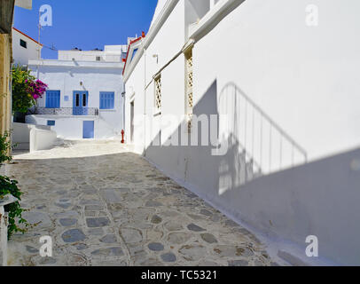 Bella tranquilla lastricata in pietra vicolo vuoto, case bianche con finestre blu a mezzogiorno tempo balcone ombra e idrante di fuoco Tinos Island, Grecia. Foto Stock