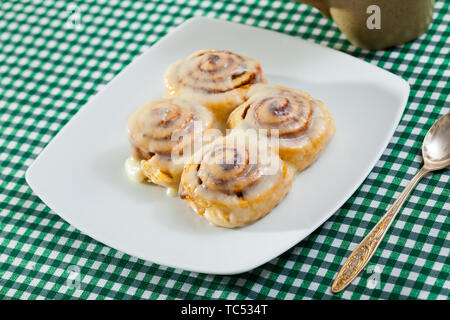 Laminati appetitosi panini alla cannella in zucchero e vaniglia ciliegina sulla piastra bianca Foto Stock