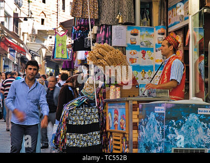 Istanbul, Turchia - 05/24/2010: Giovani dondurma gelato venditore vestito in turco tradizionale in costume street negozio di alimentari e la folla in strada del mercato. Foto Stock