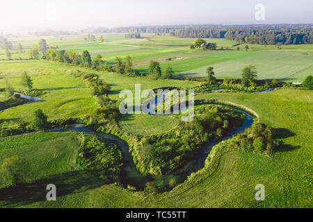 Un serpeggiante fiume circondato da prati verdi Foto Stock