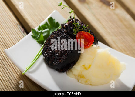 Spagnolo tradizionale salsiccia di sangue con riso servito con purè di patata e di pomodoro ciliegino e verdi Foto Stock