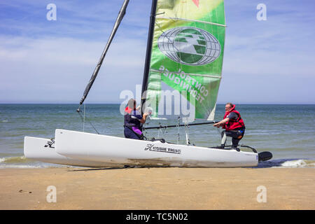 Due marinai preparazione Hobie Cat, piccolo catamarano a vela sulla spiaggia lungo la costa del Mare del Nord Foto Stock