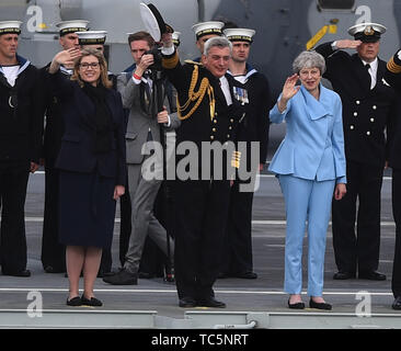 Il Segretario della Difesa Penny Mordaunt (sinistra) primo signore del mare e capo del personale navale Ammiraglio Sir Philip Jones e il Primo Ministro Theresa può stazionare sul ponte della HMS Queen Elizabeth come essi onda veterani off a bordo della MV Boudicca, come le vele al di fuori del porto di Portsmouth per lui il porto di Le Havre in Francia come parte delle commemorazioni per il settantacinquesimo anniversario dello sbarco in Normandia. Foto Stock