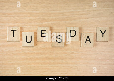 La parola Martedì, farro con tegole di legno su un effetto legno sfondo. Foto Stock