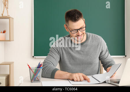 Bello insegnante maschio controllo compiti in classe Foto Stock