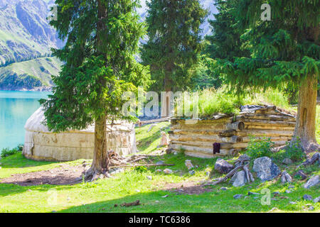 In estate, le case di legno di pastori kazake sono ricoperte di erba sul bordo di Tianchi in montagna Tianshan Foto Stock