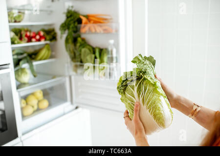 Donna prendendo cavolo fresca dal frigorifero a casa, vista da vicino Foto Stock