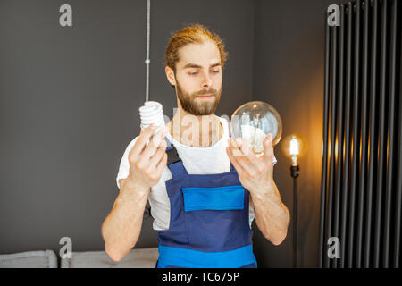 Tuttofare scegliendo tra risparmio energetico e lampadine tradizionali a casa Foto Stock