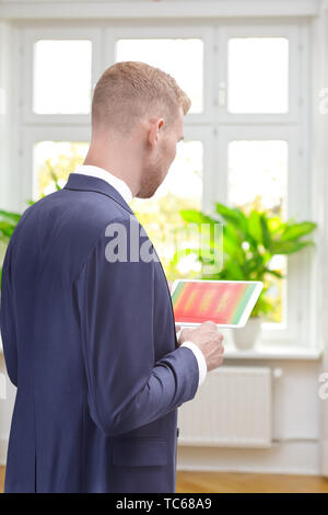 Maschio consulente energetico in una stanza di un vecchio edificio con un'immagine a raggi infrarossi di windows sul suo computer tablet Foto Stock