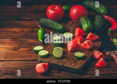 Verdure a fettine. Pomodori, cetrioli e peperoncino su sfondo di legno. Foto Stock