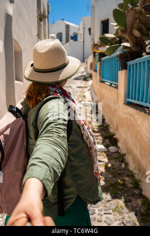 Coppia giovane in viaggio. Donna che mantiene la mano di uomo e apre la strada a nuovi luoghi e belle destinazioni, Shot nell isola greca di Santorini Foto Stock