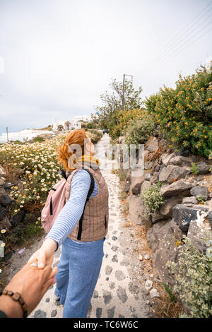 Coppia giovane in viaggio. Donna che mantiene la mano di uomo e apre la strada a nuovi luoghi e belle destinazioni, Shot nell isola greca di Santorini Foto Stock