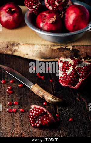 Frutti di melograno con coltello su tavola in legno rustico Foto Stock