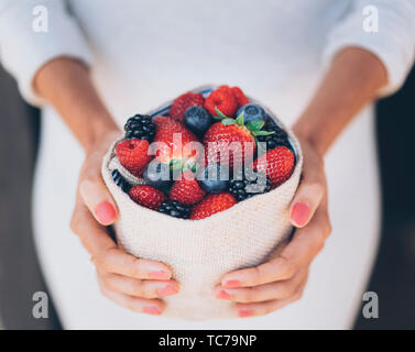 Una sana e succosa e frutti di bosco con la donna con le mani abito bianco Foto Stock