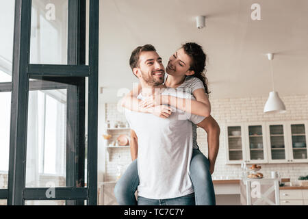 Ridendo uomo barbuto che trasportano ragazza sovrapponibile a casa Foto Stock