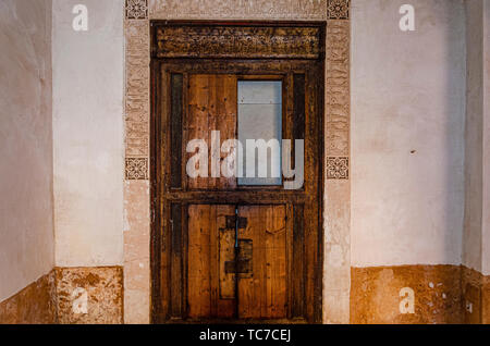 Vecchio e rustico arabo porta in legno con arabeschi di telaio lavorato in stucco. marrakech marocco Foto Stock