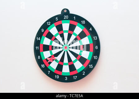 Dartboard con un dardo su un muro grigio close up Foto Stock